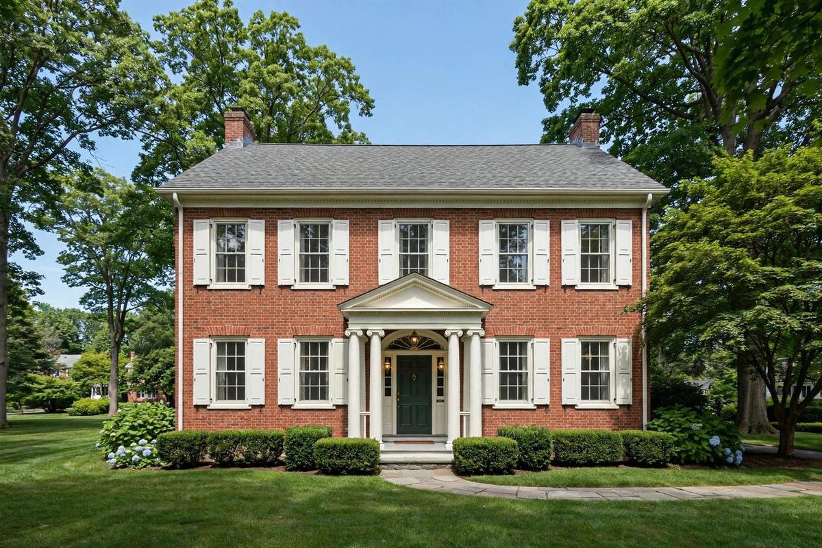 Upscale white-clapboard Connecticut Colonial in Fairfield, Connecticut with black shutters and manicured lawn.