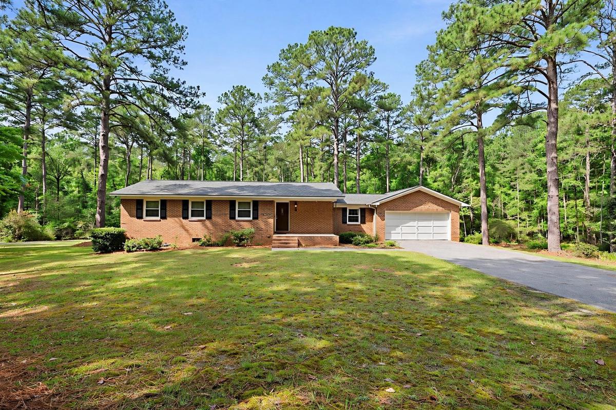 Exterior of an upscale traditional brick suburban home in Raleigh, North Carolina with a manicured lawn on a clear day.